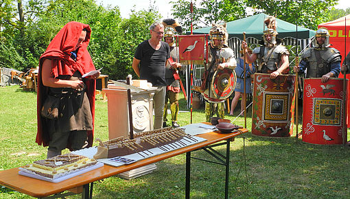 libatio des centurio classicus der Regina (Frank Schad), rechts im Bild: Dr. Heinrich Konen (Projektleiter), der zuvor eine Lusoria-Torte (Vordergrund) erhalten hatte | Foto/Bildrechte: Peter Pavlas